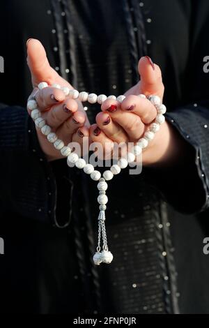 Nahaufnahme einer muslimischen Frau Hände in Abaya, während sie den Rosenkranz mit ihren Händen hält und betet. Religion beten Konzept. Vereinigte Arabische Emirate Stockfoto