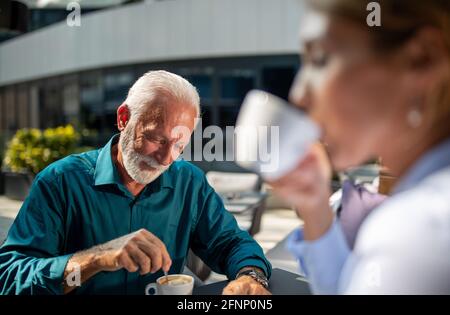 Glücklicher reifer Mann, der im Café im Freien mit einem jungen Unternehmen sitzt Frau Stockfoto