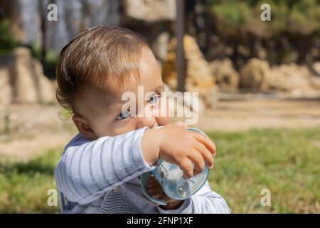 Junge trinkt seine Flasche in einem Park Stockfoto