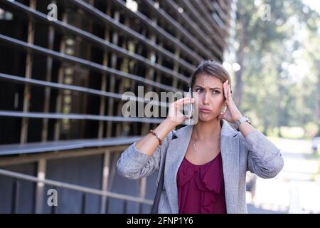 Gestresste junge Geschäftsfrau, die vor dem Telefon sprach Des Bürogebäudes Stockfoto