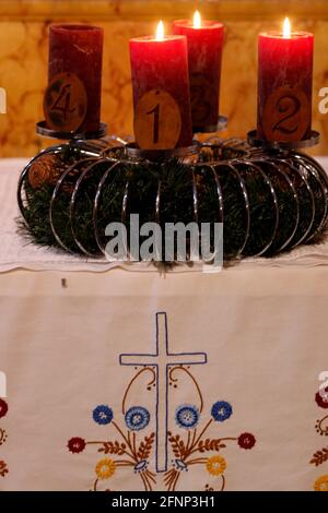 Natürlicher Adventskranz oder Krone in einer katholischen Kirche mit drei brennenden roten Kerzen. Frankreich. Stockfoto