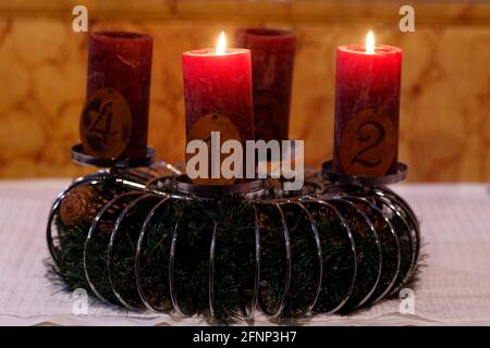 Natürlicher Adventskranz oder Krone in einer katholischen Kirche mit zwei brennenden roten Kerzen. Frankreich. Stockfoto