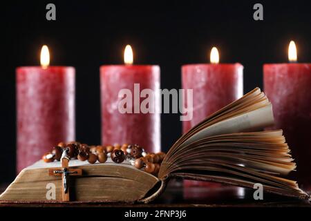 Offene bibel, Rosenkranz und Adventskranz mit vier brennenden roten Kerzen. Weihnachtskomposition. Frankreich. Stockfoto