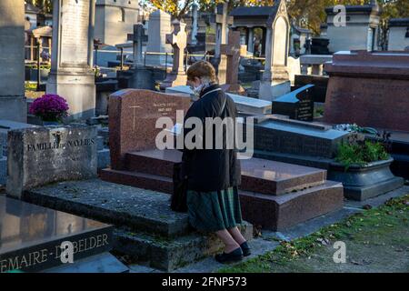 Frau, die auf dem Friedhof von Montparnasse kniet und betet (französisch: cimetiere du Montparnasse), Paris, Frankreich Stockfoto