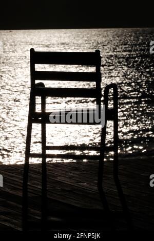Leere Stuhlsilhouette gegen Meerwasser bei Sonnenuntergang. Cannes. Frankreich. Stockfoto
