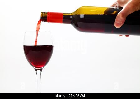 Bild eines mannes Hand Gießen Rotwein aus einem Weinflasche in ein Weinglas Stockfoto