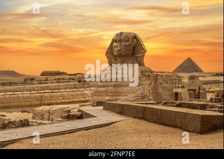 Landschaft mit ägyptischen Pyramiden, großer Sphinx und Silhouetten Antike Symbole und Wahrzeichen Ägyptens für Ihr Reisekonzept nach Afrika in goldener Sonne Stockfoto