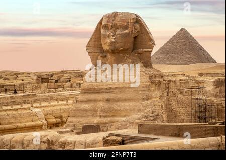 Gesamtansicht der Pyramiden mit Sphinx. Die Sphinx in Gizeh Pyramidenkomplex bei Sonnenuntergang. Unglaubliche Aussicht auf das Gesicht der Sphinx und die große Pyramide. t Stockfoto