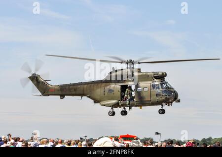 Helikopter der Royal Air Force, RAF, Puma mit Abflug bei Royal International Air Tattoo, RIAT, RAF Fairford, Großbritannien. Der Mann, der aus der Tür hing und die Menge beobachtete Stockfoto