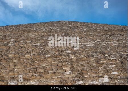 Große Pyramide von Gizeh. Blick auf die große Pyramide von Cheops vom Fuß. Pyramidenwand, alte Steinblöcke, blauer Himmel mit Wolken. Dreieckiges fa Stockfoto