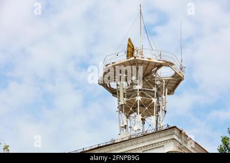 Metallturm auf dem Dach des Hauses mit verschiedenen Antennen der Mobilfunk- und Satellitenkommunikation vor dem Hintergrund des bewölkten Himmels. Stockfoto