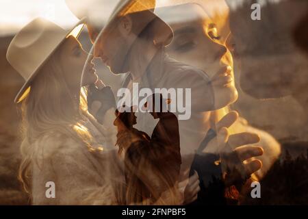 Doppelbelichtung des stilvollen Paares, das auf dem Feld steht und sich sanft umarmt. Schöne Frau mit hübscher Mann in Cowboy-Hüten genießen Momente zusammen Stockfoto