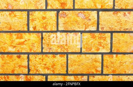 Der Hintergrund und die Textur der Wand sind aus gehauenen hellgelben Steinen in Form von unregelmäßigen rechteckigen Steinfliesen. Nahaufnahme. Stockfoto