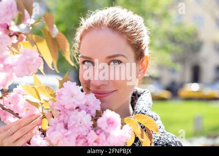 Glückliche junge fröhliche kaukasische Rotschopf Frau mit Kirschbaum Zweig Stockfoto