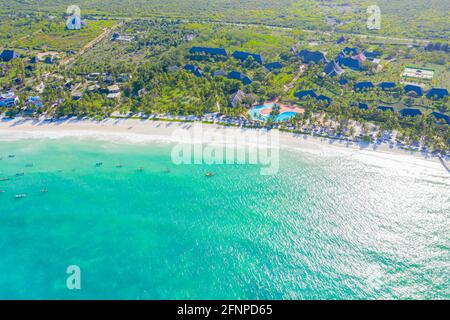 Luftaufnahme von tropischen Sandstrand mit Palmen und Sonnenschirme am sonnigen Tag. Sommer Urlaub am Indischen Ozean, Sansibar, Afrika. Landschaft mit Palmen Stockfoto