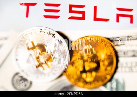 Goldmünzen einer Kryptowährung, US-Dollar und das Tesla-Firmenlogo auf weißem Hintergrund Stockfoto