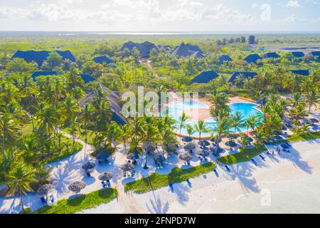 Luftaufnahme von tropischen Sandstrand mit Palmen und Sonnenschirme am sonnigen Tag. Sommer Urlaub am Indischen Ozean, Sansibar, Afrika. Landschaft mit Palmen Stockfoto