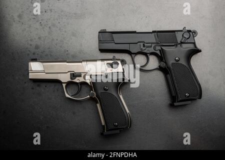 Zwei Pistolen, schwarz und silber auf metallisch grauem Hintergrund. Kurzwaffe für Verteidigung und Angriff. Stockfoto