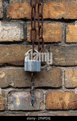 Altes Vorhängeschloss mit Kette an einer Ziegelwand Stockfoto