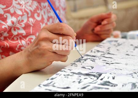 Malen nach Zahlen. Die Hand hält einen Pinsel und malt. Hobby Stockfoto