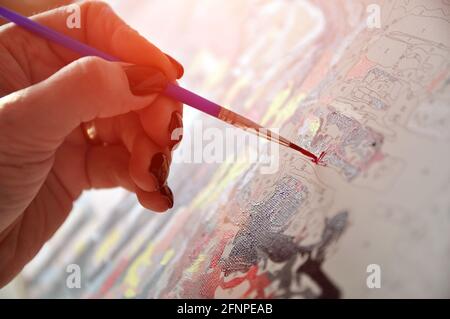 Malen nach Zahlen. Die Hand hält einen Pinsel und malt. Hobby Stockfoto