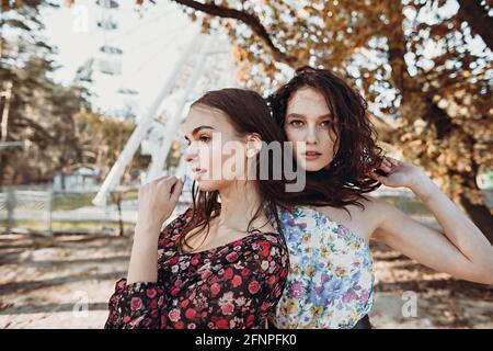 Zwei junge Frauen in Vintage-Kleidern stehen im Herbst umarmt parken Stockfoto