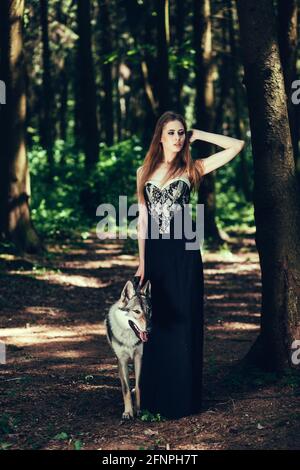 Porträt einer Frau in einem schwarzen Kleid mit Ein Hund im Wald Stockfoto