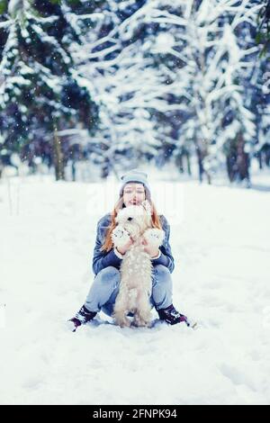 Kleiner Hund mit Besitzer verbringen einen Tag im Winter Wald spielen und Spaß haben Stockfoto