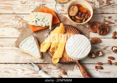 Verschiedene Käsesorten, Trockenfrüchte und Nüsse auf hellem Holzhintergrund Stockfoto