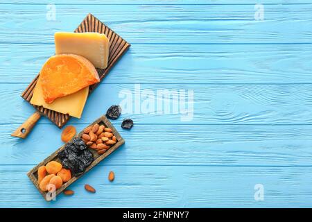 Tafel mit verschiedenen Käsesorten, getrockneten Früchten und Nüssen auf farbigem Holzhintergrund Stockfoto