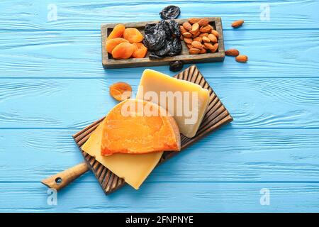 Tafel mit verschiedenen Käsesorten, getrockneten Früchten und Nüssen auf farbigem Holzhintergrund Stockfoto