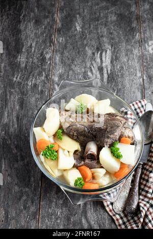 Lammkeule mit Gemüse im Glastopf Holztisch Stockfoto