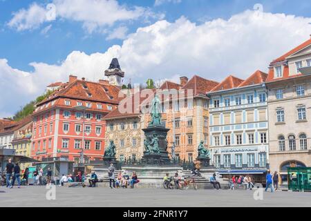 Graz, Österreich-25. April 2021: Menschen entspannen auf dem schönen Hauptplatz Hauptplatz, mit dem berühmten Uhrturm auf dem Schlossberg im Hintergrund, in s Stockfoto