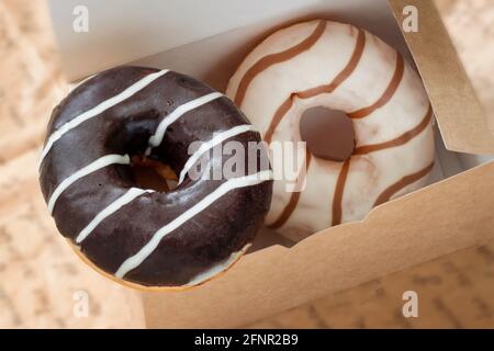 Schokolade- und Karamell-Donuts in einer Kartonschachtel in Nahaufnahme. Verkauf, Kauf, Lieferung von Backwaren, Online-Shop Stockfoto