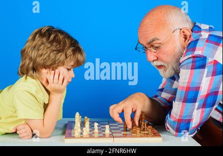 Enkel spielt Schach mit Opa. Großvater lehrt Enkelkind spielen Schach. Familienbeziehung. Stockfoto