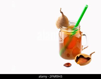 Tamarindus indica - Tamarindensaft in einem Glas, umgeben von Frische reife Tamarinden Stockfoto