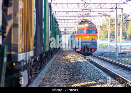 Kemerowo, Russland 27. august 2019. Der Zug der Russischen Eisenbahn fährt in einem stehenden Güterzug Stockfoto