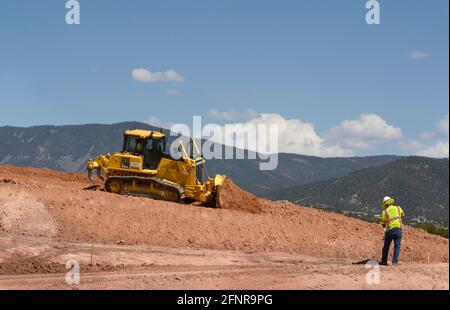 Ein Arbeiter verwendet einen Komatsu 65EX-Planierraupen, um Schmutz auf einer Baustelle für Straßenverbesserungen in Santa Fe, New Mexico, zu bewegen. Stockfoto