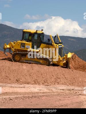 Ein Arbeiter verwendet einen Komatsu 65EX-Planierraupen, um Schmutz auf einer Baustelle für Straßenverbesserungen in Santa Fe, New Mexico, zu bewegen. Stockfoto