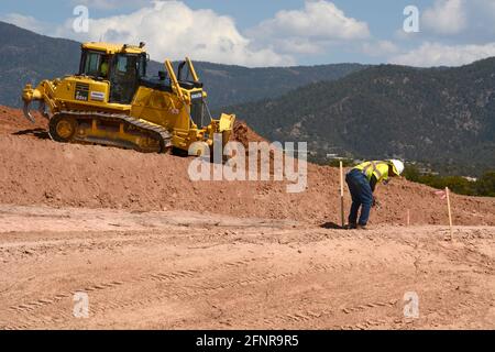 Ein Arbeiter verwendet einen Komatsu 65EX-Planierraupen, um Schmutz auf einer Baustelle für Straßenverbesserungen in Santa Fe, New Mexico, zu bewegen. Stockfoto