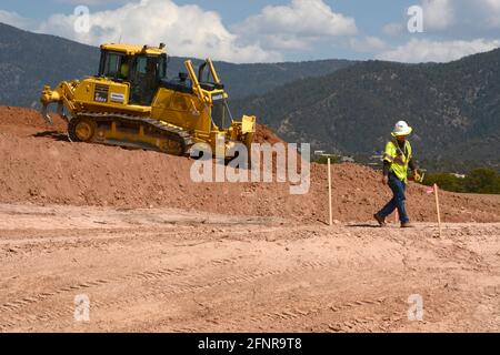 Ein Arbeiter verwendet einen Komatsu 65EX-Planierraupen, um Schmutz auf einer Baustelle für Straßenverbesserungen in Santa Fe, New Mexico, zu bewegen. Stockfoto