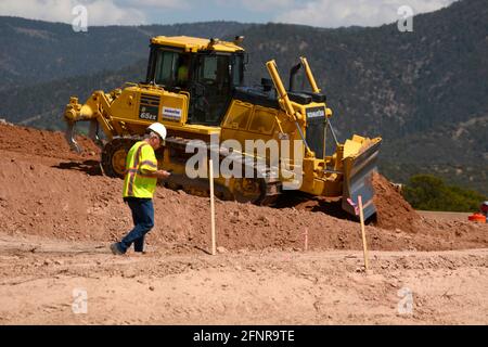 Ein Arbeiter verwendet einen Komatsu 65EX-Planierraupen, um Schmutz auf einer Baustelle für Straßenverbesserungen in Santa Fe, New Mexico, zu bewegen. Stockfoto