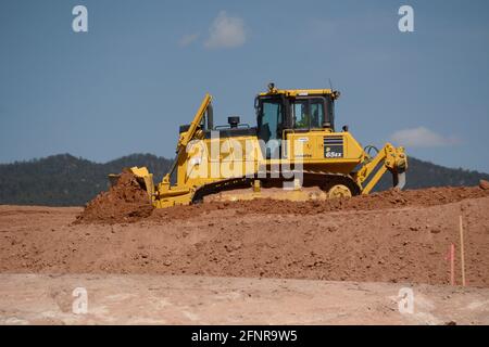 Ein Arbeiter verwendet einen Komatsu 65EX-Planierraupen, um Schmutz auf einer Baustelle für Straßenverbesserungen in Santa Fe, New Mexico, zu bewegen. Stockfoto