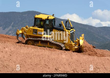 Ein Arbeiter verwendet einen Komatsu 65EX-Planierraupen, um Schmutz auf einer Baustelle für Straßenverbesserungen in Santa Fe, New Mexico, zu bewegen. Stockfoto