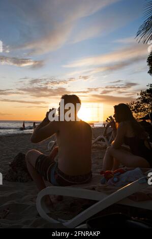 Pärchen genießen einen Drink am Strand bei Sonnenuntergang in Costa Rica Stockfoto