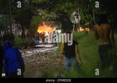 Kolumbianische Polizisten werden zwischen Demonstranten und einer brennenden Tankstelle beobachtet, die kurz zuvor explodierte, als Zusammenstöße und Unruhen Yumbo, Valle del Cauca in Kolumbien, in der Nacht zwischen Demonstranten und der kolumbianischen Bereitschaftspolizei (ESMAD) am 17. Mai in Yumbo, Valle del Cauca, Kolumbien, übernahmen. 2021. Inmitten von 20 Tagen gewalttätiger und friedlicher Proteste gegen die Regierung von Präsident Ivan Duque und Polizeibrutalität, die seit Beginn der Demonstrationen mindestens 40 Tote und 16 missbrauchte Frauen zur Folge hatte. (Foto: Mauricio Romero/Long Visual Press) Stockfoto