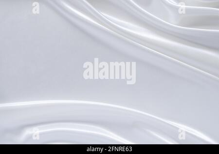 Eleganter gewellter und glatter weißer Satin-Stoff-Textur-Hintergrund. Abstraktes, Textur- und Hochzeitskonzept. Stockfoto