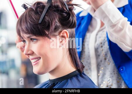 Weibliche Coiffeur Teilen Frauen Haare in Abschnitten mit Clips im shop Stockfoto