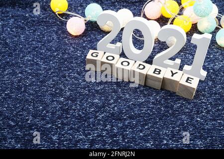 Auf Wiedersehen 2021 Buchstabe mit LED-Baumwollkugel auf blauem gestricktem Stoffhintergrund dekorieren Stockfoto