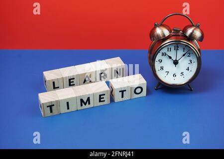 Zeit zum Erlernen des Buchstabens mit Wecker auf blauem und rotem Hintergrund Stockfoto